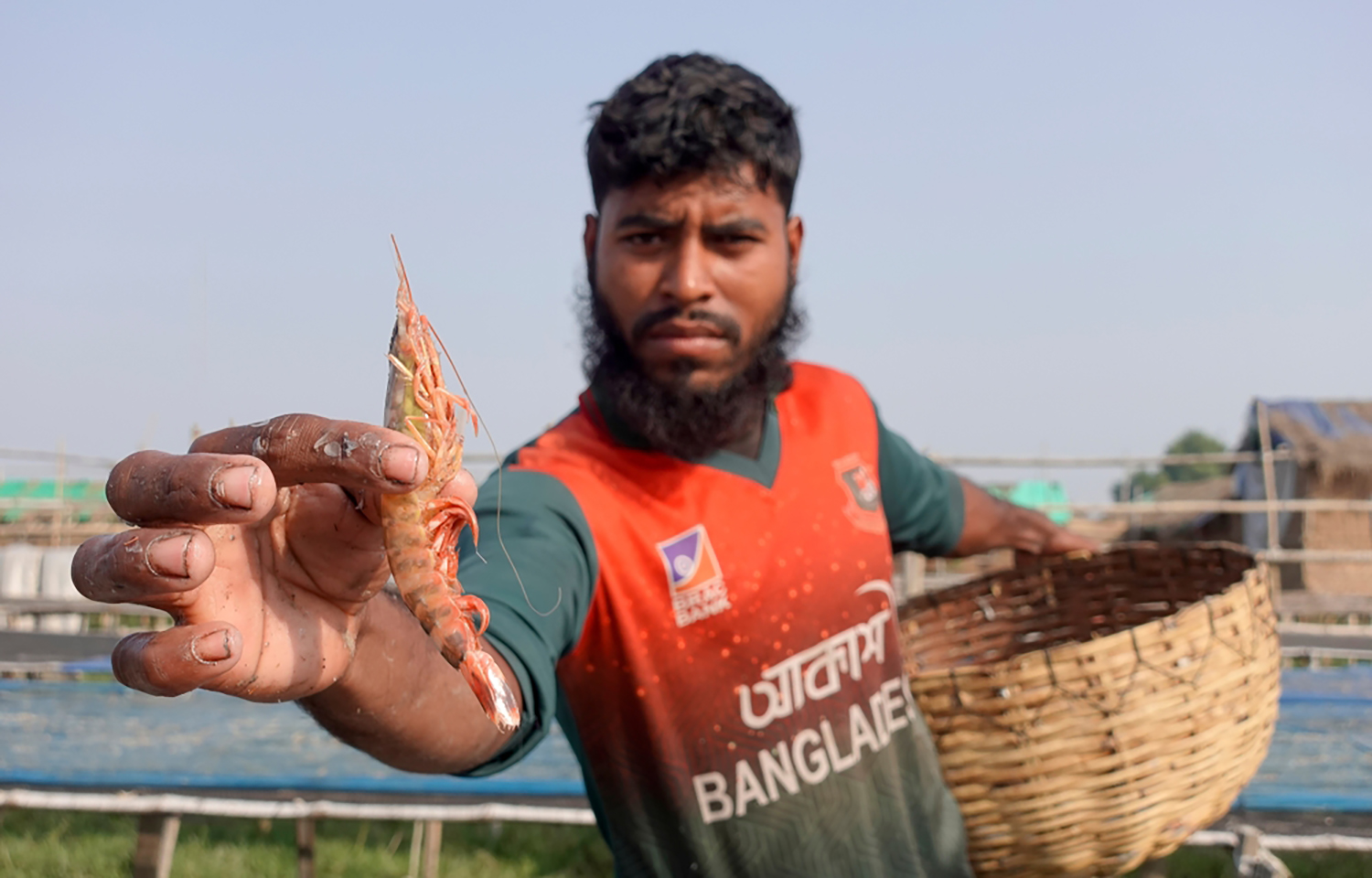 A Bangladeshi shrimp farmer holding up a shrimp