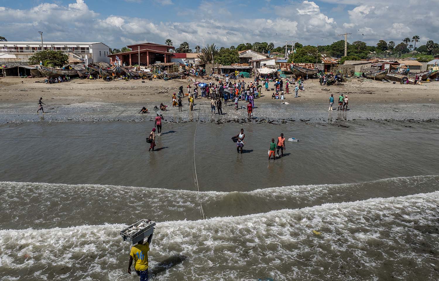 Workers carry crates of fish to shore in Gunjur, Gambia, in 2019