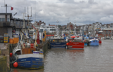 Several boats tied up to a wharf in a harbor in the United Kingdom.