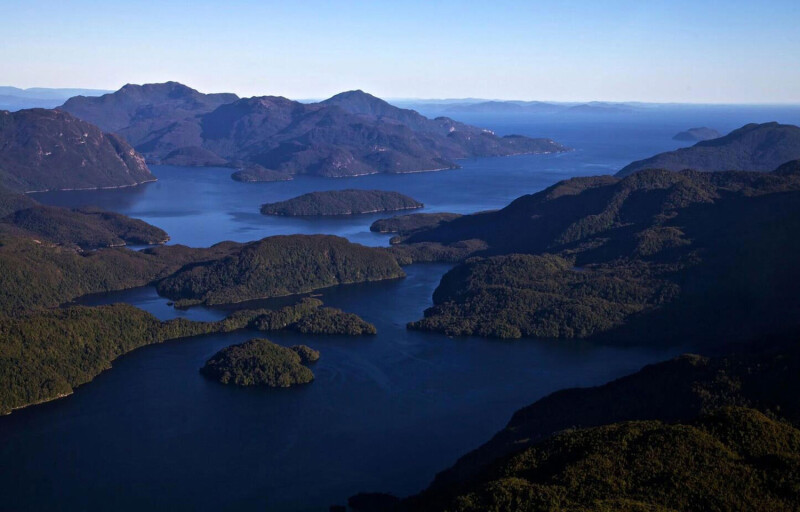 An aerial shot of Isla Magdalena National park in Chile showing deep blue water and rising green mountains