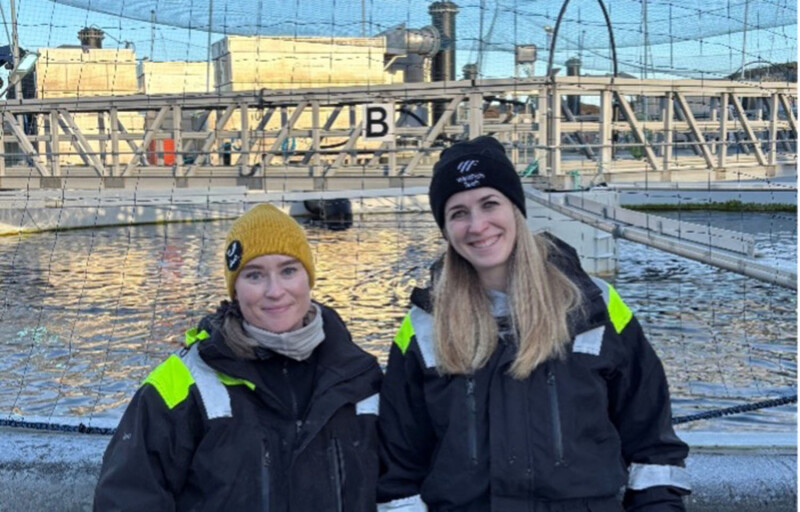 Two people standing at a salmon farm
