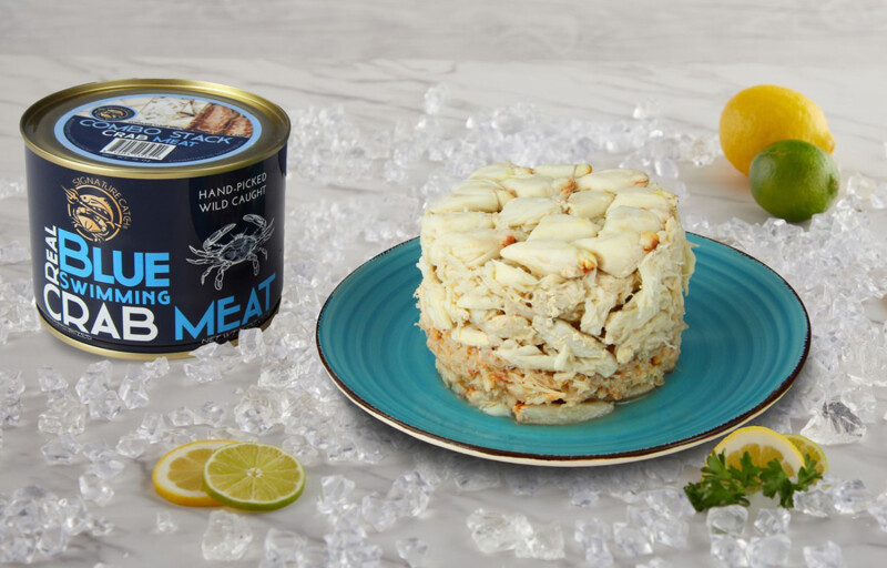 A pile of crab on a plate next to a can featuring the product label