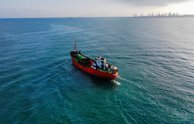 A red vessel sailing across the ocean