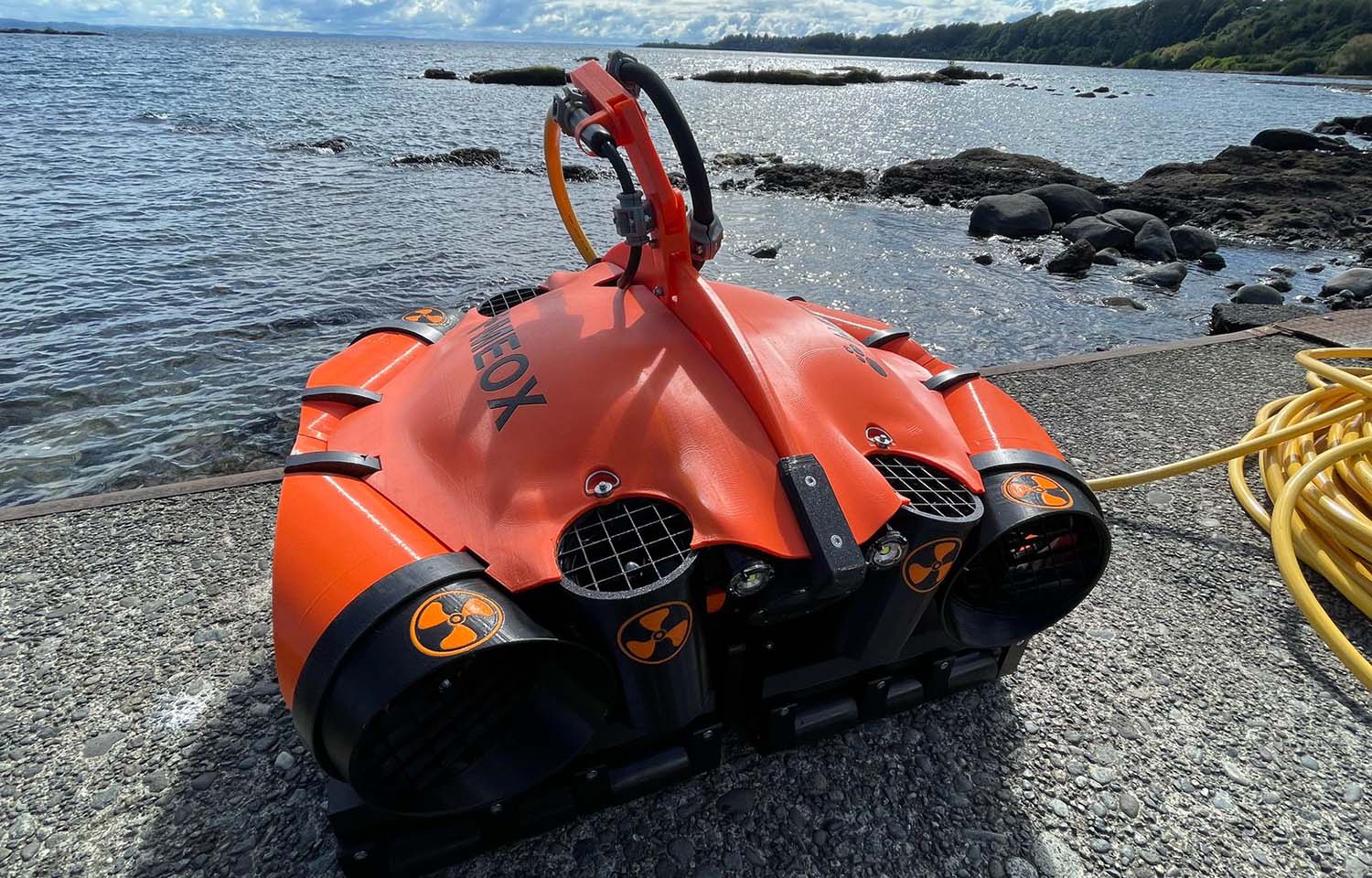 A Meox robot sitting on a dock next to the water