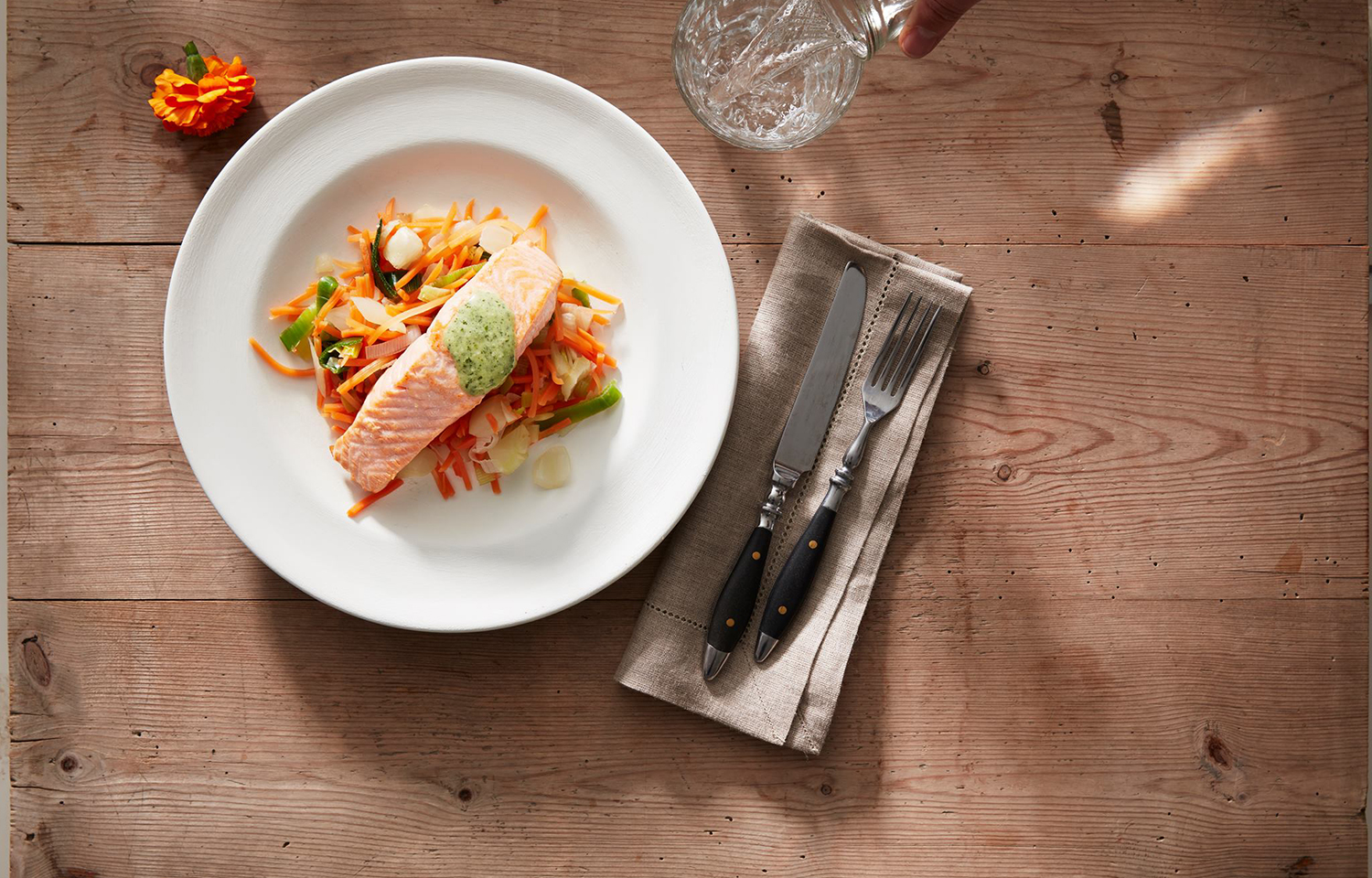 A piece of salmon on a plate on a wooden table.