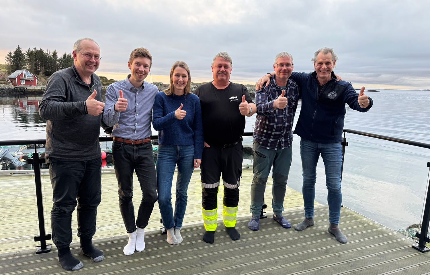 Staff of both Firda Seafood Group and Landøy Fiskeoppdrett posing on a dock in Norway