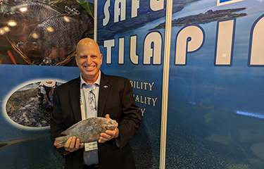 Ron Risher posing with one of the company's tilapia during Seafood Expo Asia