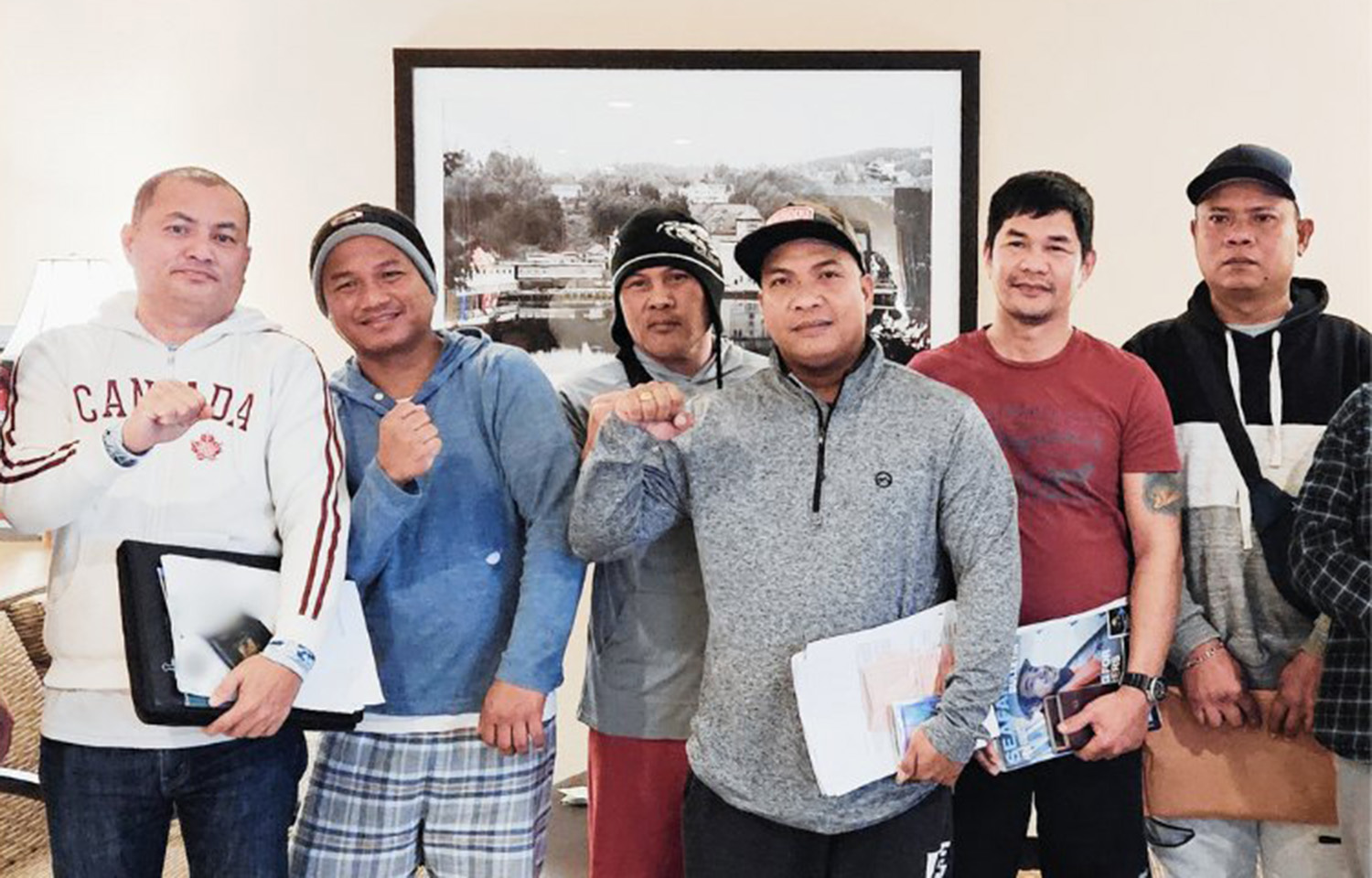 A group of six Filipino men in sweaters holding up their fists