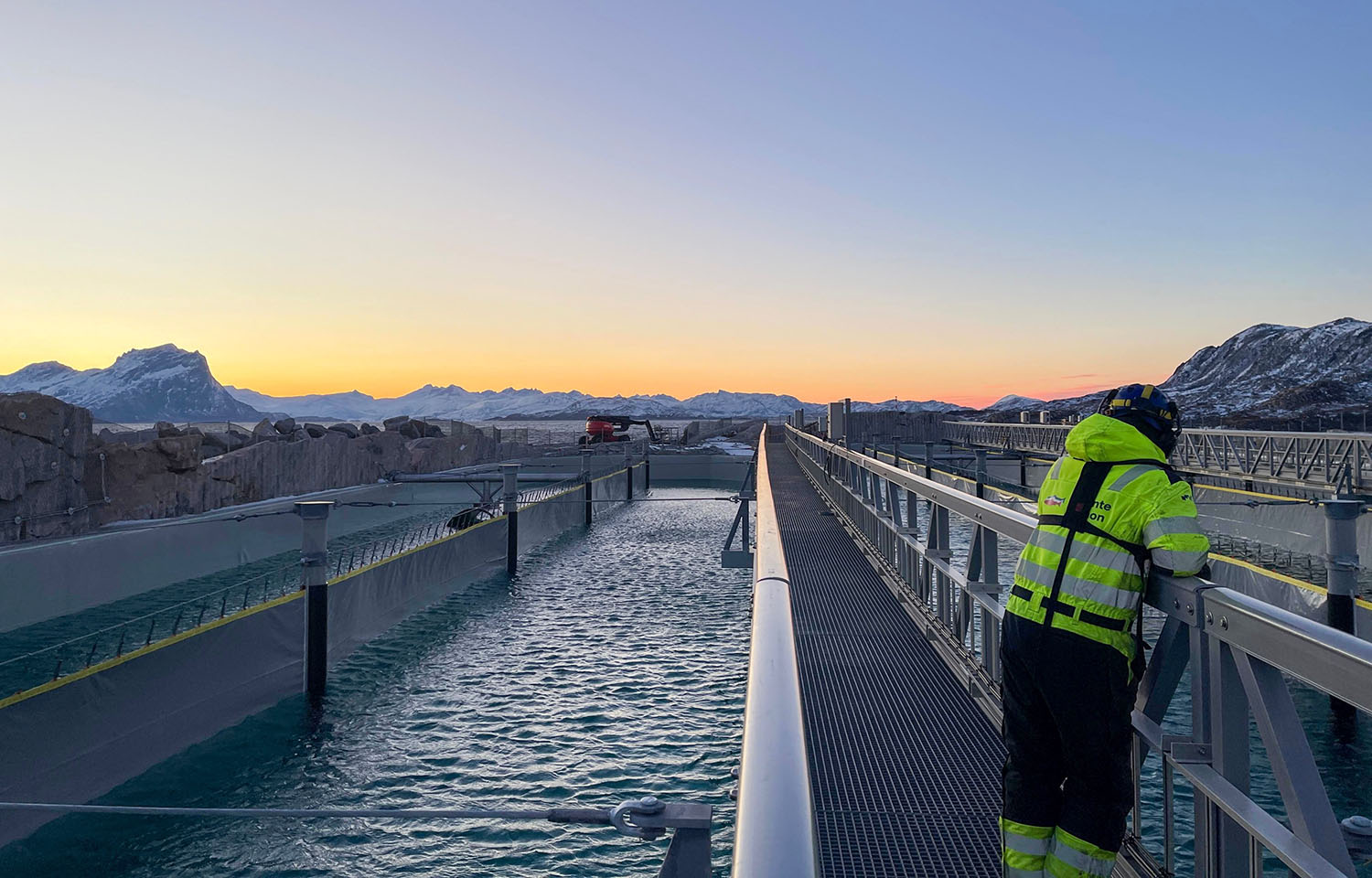 A man standing on a walkway at Gigante Salmon's flow-through aquaculture facility