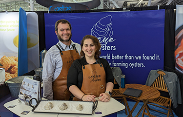 The founders of Rogue Oysters posing in their booth at Seafood Expo North America