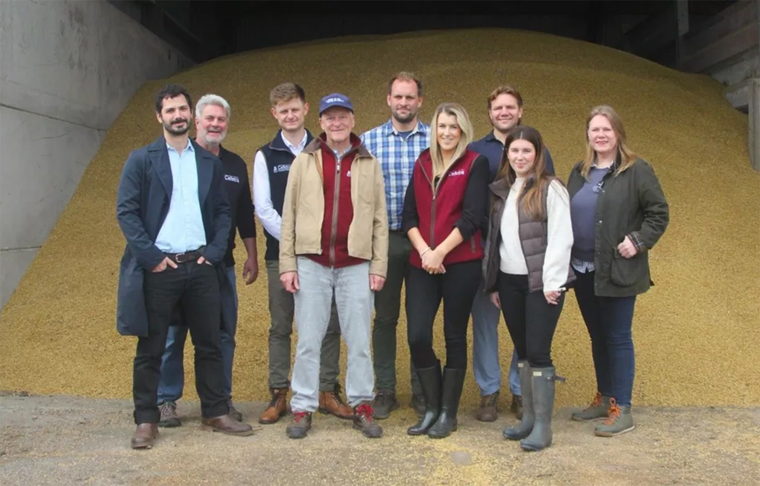 A group of staff from BioMar and Cefetra standing in front of a pile of grain