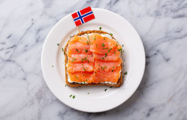 A piece of toast with smoked salmon and a Norwegian flag.