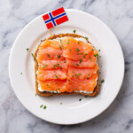 A piece of toast with smoked salmon and a Norwegian flag.