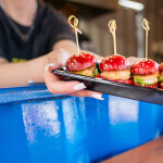 A woman holding out mini shrimp burgers on a tray