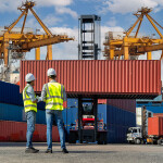 Two people in front of a shipping container at a port