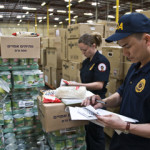 Two FDA inspectors examine food in a warehouse.