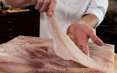 A chef holds up a fillet of Alaska pollock.