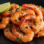 Cooked shrimp on a plate with a wedge of lime.