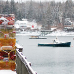 Lobster boats and traps in a harbor, all covered in snow.