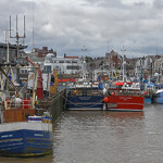 Several boats tied up to a wharf in a harbor in the United Kingdom.