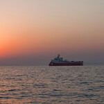 A fishing vessel at sea during a sunset.