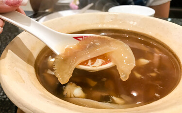 A person taking a spoonful of shark-fin soup.