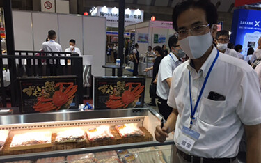 Satoru Kasei of Tsukiji Kansho next to packages of crab his company produces.