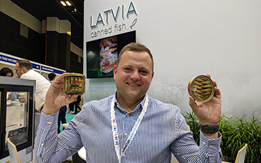 Riga Gold Senior Export Representative Igors Puzs holds up examples of the company's packaged seafood.
