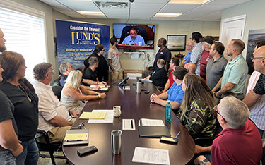A group of employees for Lund's Fisheries sit around a conference table.