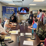A group of employees for Lund's Fisheries sit around a conference table.