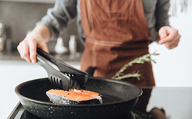 A woman cooking a salmon steak.