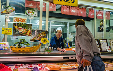 A Japanese shopper talks with an employee at a seafood market.