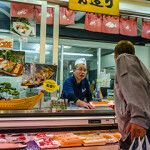A Japanese shopper talks with an employee at a seafood market.