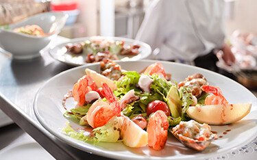 Restaurant chefs prepare a shrimp dish for diners.