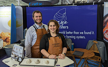 The founders of Rogue Oysters posing in their booth at Seafood Expo North America