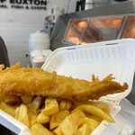 Someone holding up fish and chips from a shop in the U.K.