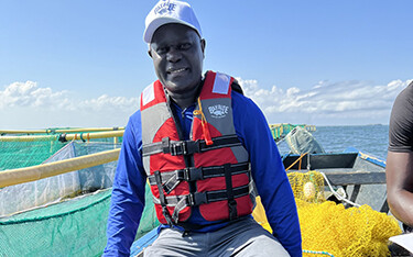 Alfred Achar of Bayrise Fish Farm on a boat near one of his aquaculture net pens.