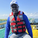 Alfred Achar of Bayrise Fish Farm on a boat near one of his aquaculture net pens.