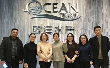 Ocean Treasure's staff posing in front of the company's logo.