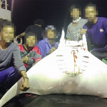 Fishers aboard an Ocean Family vessel pose with a ray they caught as bycatch