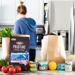 A woman in a kitchen with bags of MSC-certified seafood products