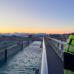 A man standing on a walkway at Gigante Salmon's flow-through aquaculture facility