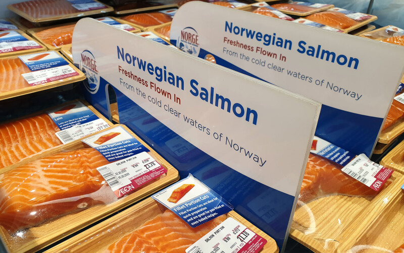 A sign promoting Norwegian salmon in a seafood case