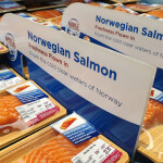A sign promoting Norwegian salmon in a seafood case