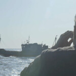 Ian Urbina looking through binoculars at a fishing vessel