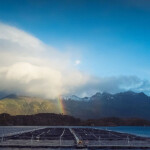 A Cermaq-owned salmon farm in Canada with a rainbow and mountains in the background.