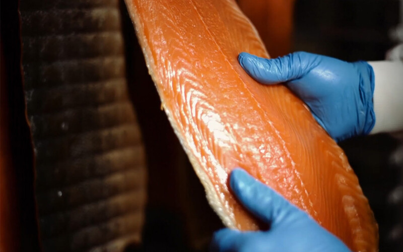 A worker handling some of Associated Seafoods' smoked salmon