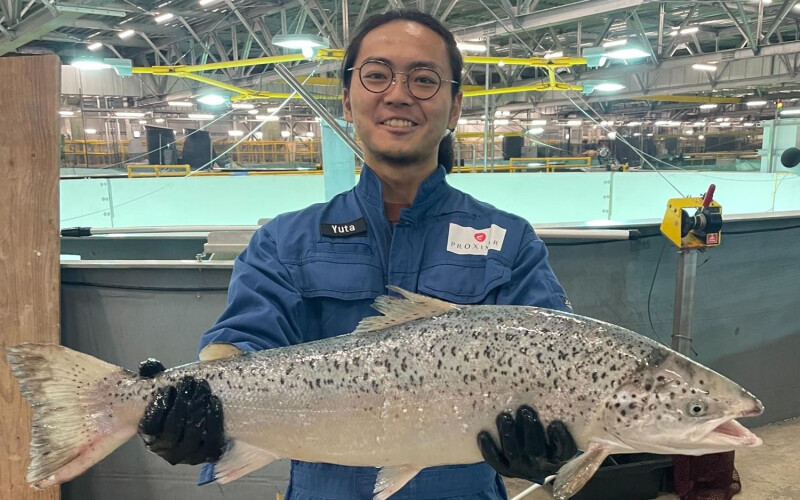 A Proximar Seafood employee holds up a salmon farmed in its facility