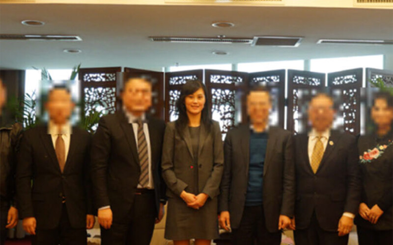 A photo of Linda Sun with several Chinese officials, with the officials' faces blurred.