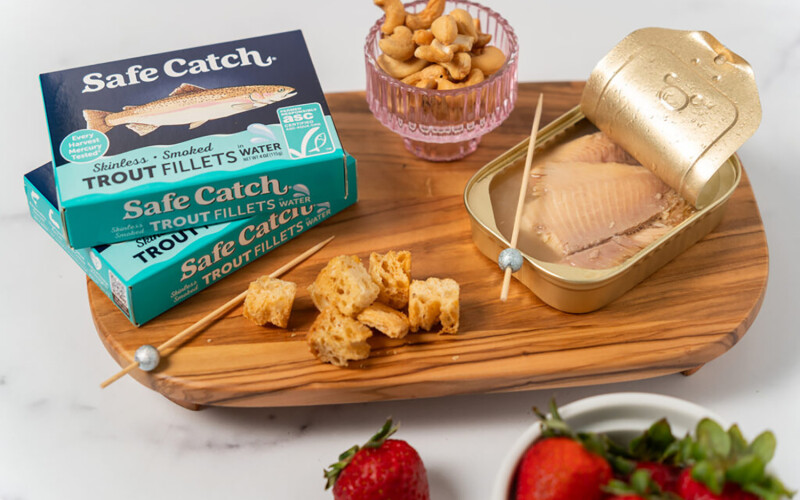 Safe Catch tinned trout on a charcuterie board with croutons and nuts